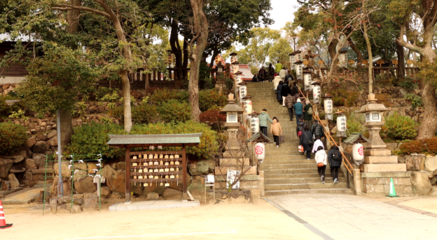 Ihmisiä kävelee shintopyhäkön rappusilla. 