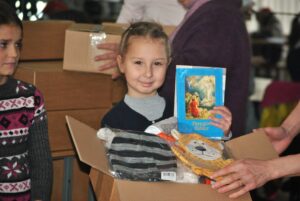 Moldovalainen tyttö esittelee joulupakettiin kuuluvaa Raamatun kertomuksia lapsille -kirjaa. Kuva: Tabea